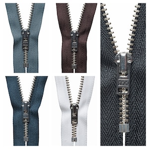 May include: A close-up of five different zipper pulls. The zipper pulls are all metal and have a silver finish. The zipper pulls are attached to different colored fabrics, including blue, brown, white, and black.