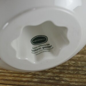 May include: White ceramic bowl with a star-shaped base. The bowl features a floral design with butterflies and the text "Portmeirion Susan Williams-Ellis Botanic Garden".