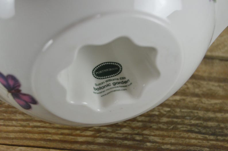 May include: White ceramic bowl with a star-shaped base. The bowl features a floral design with butterflies and the text "Portmeirion Susan Williams-Ellis Botanic Garden".