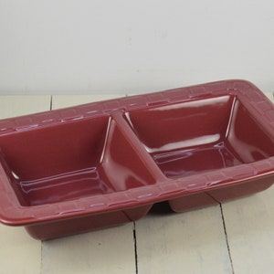 May include: A divided serving dish made of red ceramic with a woven pattern around the rim.