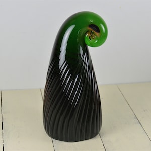 May include: A green glass sculpture with a spiral design. The sculpture is made of dark green glass with a lighter green spiral on top.