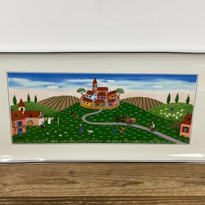 May include: Rectangular ceramic serving platter with a painted village scene. The artwork depicts a village with red-roofed buildings, a winding road, and figures. The platter has a white background with a dark brown border.