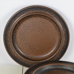 May include: Two brown ceramic dinner plates with a black rim. The plates have a speckled glaze.