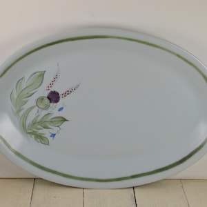 May include: A white oval serving platter with a green border and a painted design of a thistle flower with green leaves and blue flowers.