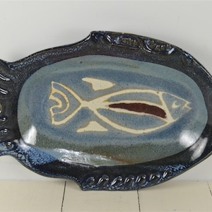 May include: A blue and white ceramic fish-shaped serving dish with a brown fish design in the center.