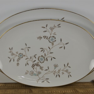 May include: Two white oval serving platters with gold trim and a delicate floral design in brown and blue.