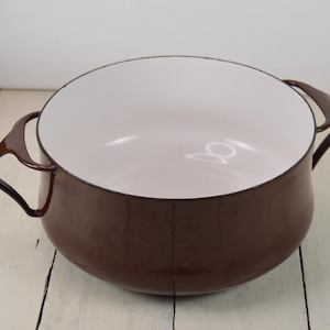 May include: A brown enameled cast iron pot with white interior and two loop handles.