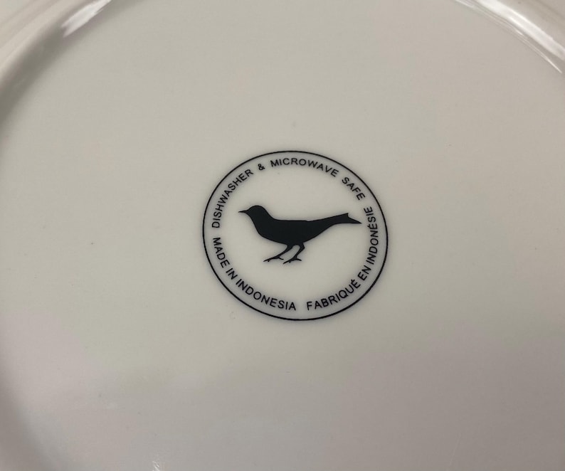 May include: White ceramic plate with a black bird silhouette in a circular design. Text around the bird reads "Dishwasher & Microwave Safe" and "Made in Indonesia Fabriqu&eacute; en Indon&eacute;sie".