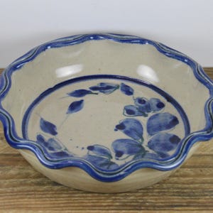 May include: A white ceramic pie plate with a blue floral design and a scalloped edge.