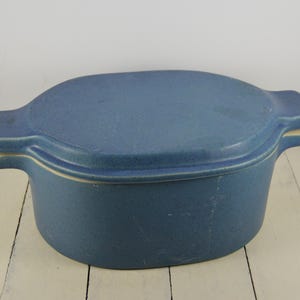 May include: A blue ceramic oval baking dish with a lid. The dish has a white rim and a slightly textured surface.