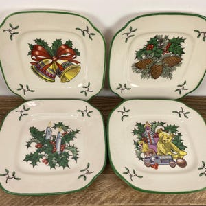 May include: Set of four square ceramic plates with a green trim and festive holiday designs. Each plate features a different Christmas-themed illustration, including bells, pinecones, candles, and toys. The plates are off-white with green accents.