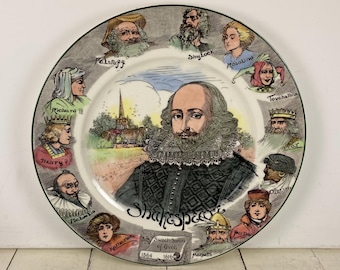 Könnte beinhalten: Ein dekorativer Keramikteller mit einem Porträt von William Shakespeare, umgeben von Illustrationen von Charakteren aus seinen Stücken. Der Teller hat einen grünen Rand und enthält Texte wie "Shakespeare" und "Sweet Swan of Avon".