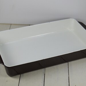 May include: A brown baking dish with a white interior. The dish is made of ceramic and has a rectangular shape.