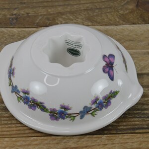 May include: White ceramic cake mold with a butterfly design and a floral border. The mold has a center hole and the words "Made in England" are visible on the bottom.