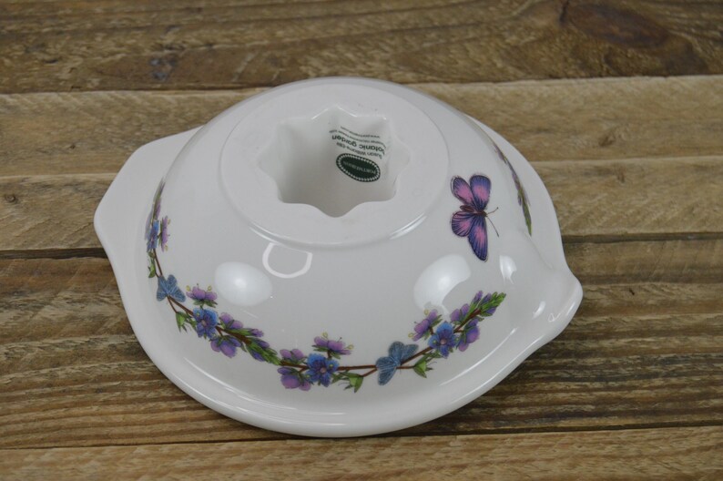May include: White ceramic cake mold with a butterfly design and a floral border. The mold has a center hole and the words "Made in England" are visible on the bottom.