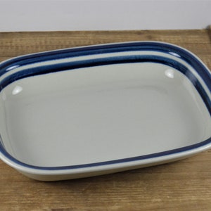 May include: A white ceramic baking dish with a blue rim and three blue stripes around the edge.