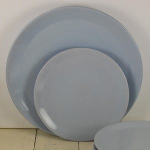 May include: Three light blue ceramic plates of different sizes stacked on top of each other.