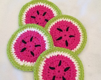 May include: Four handmade crochet coasters in a watermelon design. Each coaster features a bright pink center with black seed details, a white rind, and a green outer edge. These coasters are perfect for adding a touch of summer to your home decor.