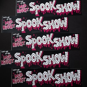 May include: Five black and pink stickers with the text "Let's go to the Mid Night Spook Show" in white lettering. The stickers have a dripping effect with pink and white paint.