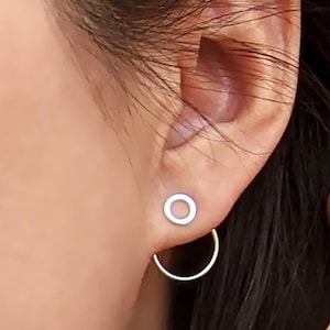 May include: A pair of silver earrings, one is a small circle stud and the other is a larger hoop earring.