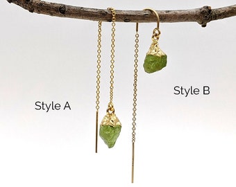 May include: Two styles of gold chain earrings with green gemstone drops. Style A has a shorter chain and a longer chain. Style B has a single chain.