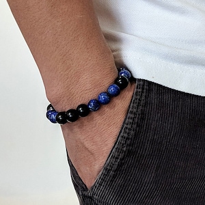 Könnte beinhalten: Ein Armband mit blauen und schwarzen Perlen. Das Armband wird am Handgelenk getragen.