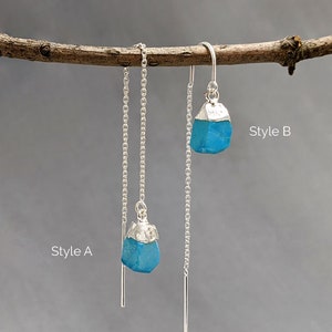 May include: Two pairs of silver chain earrings with turquoise blue gemstone pendants. The earrings are labeled "Style A" and "Style B".