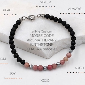 May include: A black lava stone bracelet with pink and silver beads. The bracelet is labeled "4-IN-1 Custom MORSE CODE AROMATHERAPY BIRTHSTONE CHAKRA bracelet". The words "PEACE", "SISTER", "ALWAYS", "MOM", "JOY", "XOXO", and "LAUGH" are written in Morse code above and below the bracelet.