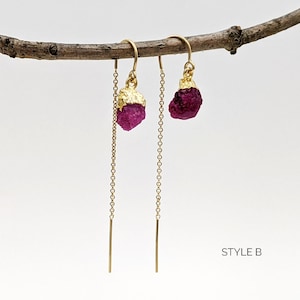 Op de afbeelding: Een paar gouden oorbellen met lange kettingen en roze robijnen. De oorbellen zijn gemarkeerd met "STYLE B".