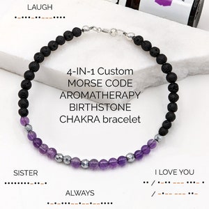Pode incluir: Um bracelete de pedra de lava preta com contas de ametista e hematita. O bracelete é personalizável com opções de código morse, aromaterapia, pedra de nascimento e chakra. O texto "TO THE MOON AND BACK", "LAUGH", "SISTER", "ALWAYS" e "I LOVE YOU" é exibido em código morse.
