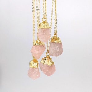 May include: Five gold-plated rose quartz pendants on delicate gold chains. The quartz is a natural, raw, and unpolished stone.