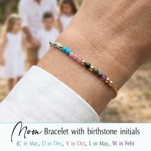 May include: A gold chain bracelet with colorful gemstone beads. The bracelet features light blue, turquoise, pink, green, and purple beads, along with gold accents. The text on the image reads "Mom Bracelet with birthstone initials".