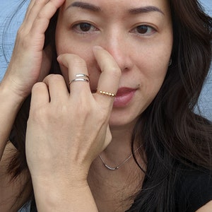 Model wearing single fidget ring with beads and hammered ends; in sterling silver and gold filled