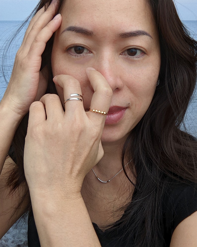 Model wearing single fidget ring with beads and hammered ends; in sterling silver and gold filled