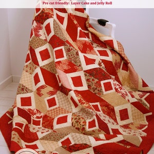 Op de afbeelding: Een rood en cr&egrave;mekleurig quilt met een geometrisch patroon van vierkanten. De quilt is over een witte stoel gegooid. De quilt heeft de titel "Ruby Squares" en is ontworpen door Rachelle Denneny. De quilt is geschikt voor voorgesneden stukken en kan worden gemaakt met een layer cake of jelly roll.