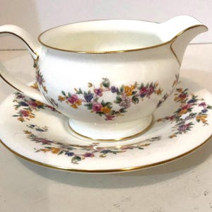 Puede incluir: Un juego de tres tazas de cerámica con un esmalte moteado de color crema. Cada taza presenta un diseño pintado a mano diferente: una hoja azul y verde, una flor amarilla y una baya roja. Las tazas tienen un diseño simple y moderno.