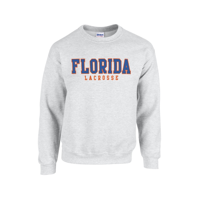 May include: A gray sweatshirt with the words "FLORIDA LACROSSE" printed on the front in blue and orange letters.