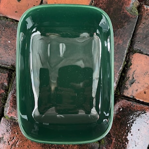 Könnte beinhalten: Eine rechteckige Backform aus dunkelgrüner Keramik. Die Form ist glasiert und hat eine glatte, glänzende Oberfläche.