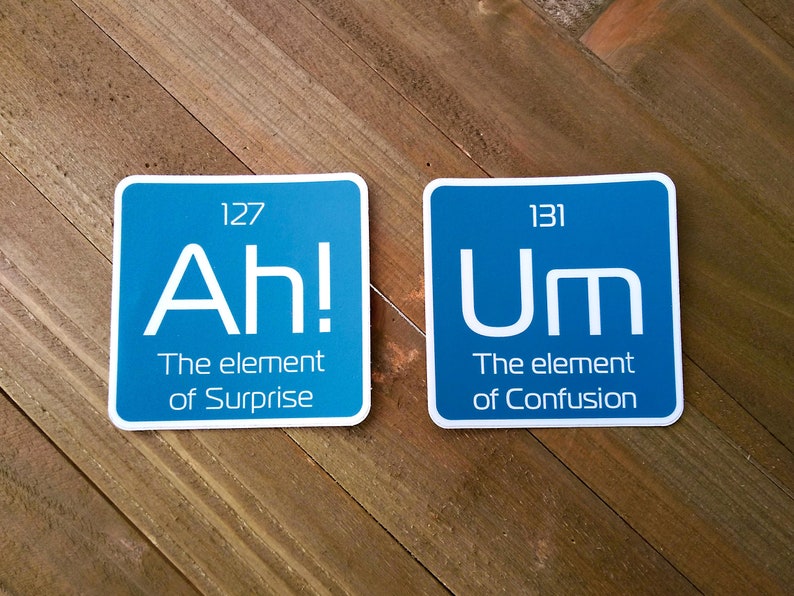 May include: Two blue square stickers with white text. The first sticker says "Ah! The element of Surprise" with the number 127 above the text. The second sticker says "Um The element of Confusion" with the number 131 above the text.