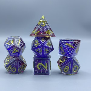 May include: A set of seven polyhedral dice in a variety of shapes, including a d4, d6, d8, d10, d12, d20, and a percentile die. The dice are purple with gold numbering and accents, and have a stained glass appearance.