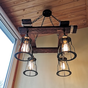 May include: A rustic wooden ceiling light fixture with four black metal cage light bulbs. The fixture is made of reclaimed wood and has a distressed finish.