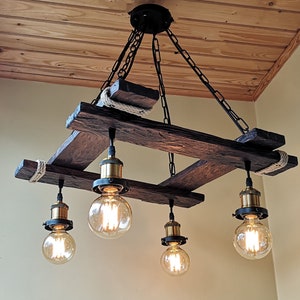 May include: A rustic wooden chandelier with five light bulbs. The chandelier is made of reclaimed wood and has a natural finish. The light bulbs are Edison-style and have a warm white glow.