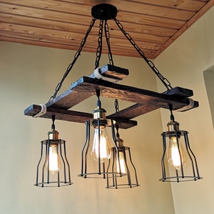 May include: A rustic wooden chandelier with five light bulbs. The chandelier is made of reclaimed wood and has a black metal frame. The light bulbs are Edison bulbs and are surrounded by black metal cages.