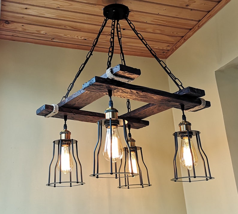 May include: A rustic wooden chandelier with five light bulbs. The chandelier is made of reclaimed wood and has a black metal frame. The light bulbs are Edison bulbs and are surrounded by black metal cages.