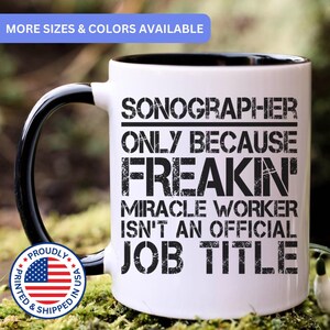 May include: A white ceramic mug with a black handle and interior, featuring the black text: SONOGRAPHER ONLY BECAUSE FREAKIN' MIRACLE WORKER ISN'T AN OFFICIAL JOB TITLE. A circular badge with the American flag and the text PROUDLY PRINTED & SHIPPED IN USA.