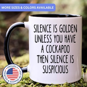 May include: A white ceramic mug with a black handle and interior, featuring the black printed text: SILENCE IS GOLDEN UNLESS YOU HAVE A COCKAPOO THEN SILENCE IS SUSPICIOUS. The mug includes a circular badge with the American flag and text.