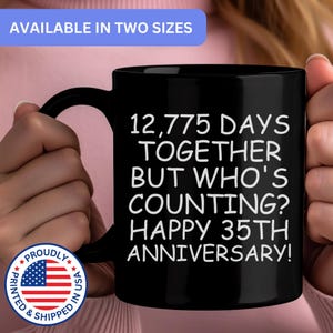 May include: A black ceramic mug featuring white text that reads 12,775 DAYS TOGETHER BUT WHO'S COUNTING? HAPPY 35TH ANNIVERSARY! The mug has a curved handle and a smooth finish, displaying the printed message clearly against the dark background.