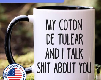 May include: A white ceramic mug with a black interior and a black handle. The mug features black text that reads: MY COTON DE TULEAR AND I TALK SHIT ABOUT YOU. The design is printed on the front of the mug in a simple, bold, sans-serif font.