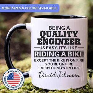 May include: A white ceramic mug with a black handle and interior, featuring the black printed text: BEING A QUALITY ENGINEER IS EASY. IT'S LIKE RIDING A BIKE EXCEPT THE BIKE IS ON FIRE YOU'RE ON FIRE EVERYTHING'S ON FIRE David Johnson.