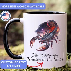 May include: A white ceramic mug with a black handle and interior, featuring a graphic of a dark scorpion set against a colorful nebula background. Below the scorpion, the text reads David Johnson Written in the Stars in black script.